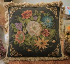 a decorative pillow with flowers on it sitting on a table next to some other items