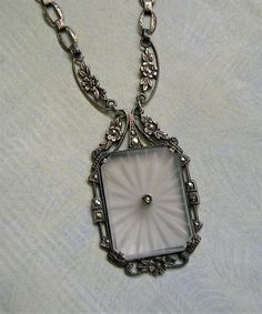 a necklace with a square shaped pendant hanging from it's side on a white surface