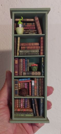 there is a miniature book shelf with books on it