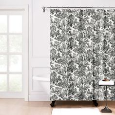 a shower curtain with a black and white floral pattern on it in front of a bathtub