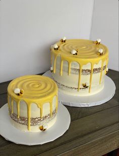 two cakes with yellow icing sitting on top of each other in front of a white wall