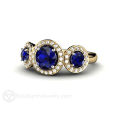 An absolutely stunning three stone ring featuring Blue Sapphires and Diamonds. Three beautiful Blue Sapphires are surrounded by halos of sparkling conflict free diamonds, 1/4ct total weight. The center Sapphire is 1ct and the two side Sapphires are approx. .37cts each. This ring is available in your choice of 14K White, Yellow or Rose Gold. Gorgeous! Sapphires are a wonderful alternatives to diamonds. With exceptional brilliance, hardness and durability, they are perfect for everyday wear. This Halo Sapphire Ring, Earth Engagement Rings, Moonstone Engagement Ring Rose Gold, Engagement Ring Three Stone, Blue Diamond Engagement Ring, Original Engagement Rings, Rose Gold Engagement Ring Vintage, Blue Sapphire Engagement Ring, Ring Three Stone