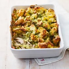 a casserole dish with chicken, broccoli and potatoes on a napkin