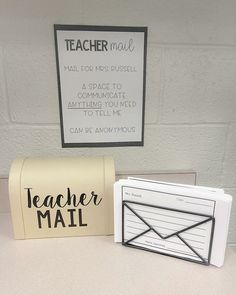 two mail boxes sitting next to each other on top of a table with a sign above them