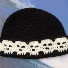 a black and white crocheted hat on top of a surfboard