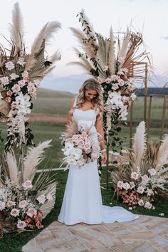 a woman standing in front of an arch with flowers