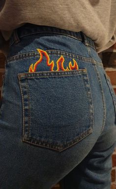 the back of a person's jeans with flames painted on their butts and knees