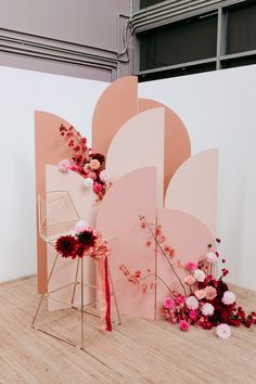 an arrangement of flowers is displayed in front of a backdrop with pink and white shapes