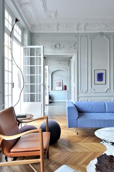 a living room with white walls and blue couches in front of an open door