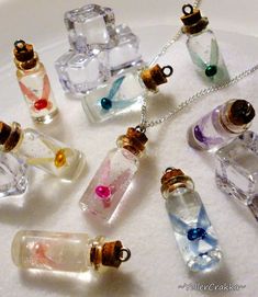 several small glass bottles with different colors and designs are on a white surface next to a silver chain