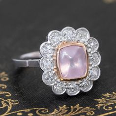 Cluster rings are a wonderful way to incorporate colored gemstones and diamonds into a piece of jewelry that is wearable just as is beautiful! A beautiful color contrast is this pink sapphire set in a halo of crisp, white old mine cut diamonds. The sugarloaf itself is bezel set in warm yellow gold, which kooks so pretty against the soft pink of the stone. All of the diamonds in platinum sparkle effortlessly, altogether making for the sweetest ring ever. Platinum and 18kt yellow gold bezel Size 6 Luxury Pink Gemstone With Center Stone, Pink Platinum Ruby Ring, Classic Pink Cluster Ring With Center Stone, Classic Pink Cluster Ring With Halo Setting, Fine Jewelry Pink Diamond Ring In Platinum, Classic Pink Diamond Cluster Ring, Pink Oval Diamond Ring In Platinum, Platinum Pink Rings With Halo Setting, Pink Platinum Jewelry With Brilliant Cut