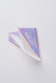 three triangular shaped papers sitting on top of a white table next to an orange and pink object