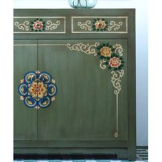 a green cabinet with painted flowers on it