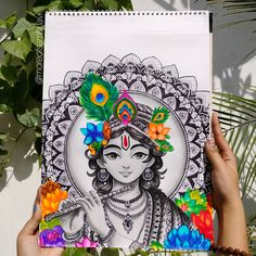 a person holding up a drawing in front of a plant with leaves and flowers on it