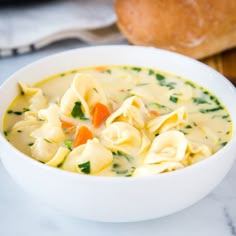 a white bowl filled with pasta and veggies on top of a marble counter