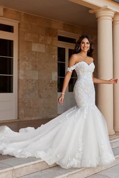 a woman in a white wedding dress posing on some steps with her arms out to the side