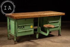 a green desk with drawers and a wooden top on the table is shown in front of a black background