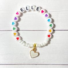 a white beaded bracelet with colorful hearts and a gold heart charm on the clasp