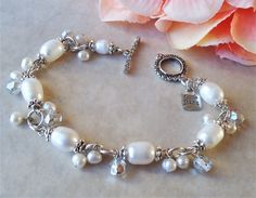 "This exquisite bracelet features white freshwater pearls which are accented with ornate pewter bead caps, all plated in 24 karat gold. This striking color combination is offset with beautiful clusters of various sized freshwater pearls and silver foiled Austrian crystal. The piece is finished with a decorative toggle closure and has my signature logo tag. The bracelet measures 7 ½\" in length. Adjustments can be made if upon request. Available in sterling silver plate. Pearls are known to symbo Elegant Silver Beaded Bracelets For Wedding, Elegant Silver Beaded Wedding Bracelets, Adjustable Pearl Bracelet With Sterling Silver Clasp, Silver Beaded Pearl Bracelet For Anniversary, Elegant Pearl Bracelet With Silver Beads For Wedding, Silver Pearl Bracelets For Mother Of The Bride, Adjustable White Pearl Bracelet For Mother Of The Bride, Nickel Free Round Beads Bracelet For Wedding, Nickel Free Wedding Bracelet With Round Beads