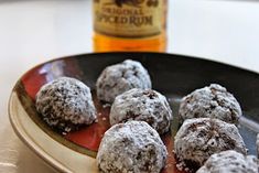 powdered sugar covered donuts on a plate next to a bottle of bourbon syrup