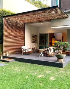 an outdoor living area with wooden slats on the wall and grass in the foreground