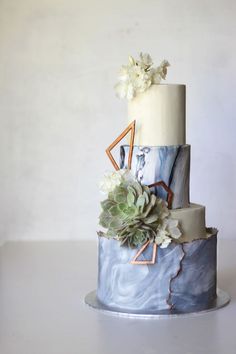 a three tiered cake decorated with succulents and flowers