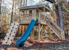 a blue slide in the woods next to a tree house