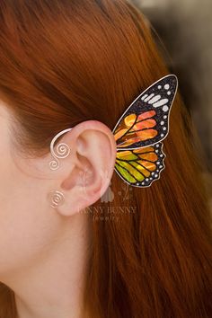 a woman with long red hair wearing a butterfly earring in the shape of a butterfly