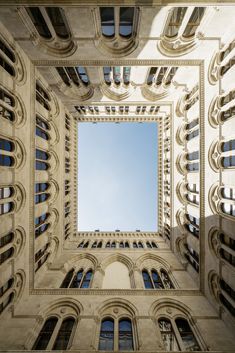 looking up at the sky through an arch in a building's facade with windows