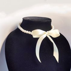 Elevate your look with this stunning Pearl Bead Necklace with ribbon bow. Crafted from high-quality plastic beads, this necklace offers the elegant appearance of pearls with the added benefit of being lightweight and comfortable to wear. Its intricate twisted design adds a touch of sophistication, making it suitable for both casual and formal occasions.

**Key Features:**
- Lightweight plastic beads
- Elegant twisted design
- Comfortable to wear all day
- Perfect for any occasion

This beautiful necklace is an ideal accessory for your wardrobe or a thoughtful gift for someone special. Add a touch of classic elegance to any outfit with Pearl Bead Necklace with ribbon bow. Pearl Necklaces With Bow For Wedding, White Pearl Jewelry With Ribbon Detail, White Pearl Jewelry With Ribbon, White Ribbon Necklace For Parties, Elegant White Ribbon Necklaces, Elegant Pearl Necklaces With Ribbon, Elegant Pearl Necklace With Ribbon, Outfit With Pearls, White Ribbon Bow