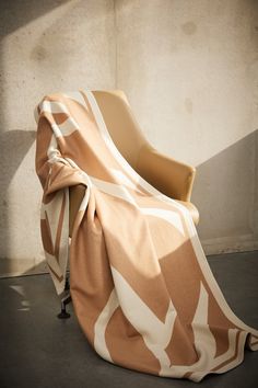 a chair with a blanket on it sitting in front of a wall