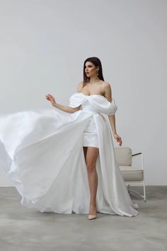 a woman in a white dress is posing for the camera with her long flowing skirt