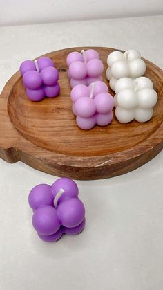 candles are arranged in the shape of flowers on a wooden tray with white and purple ones