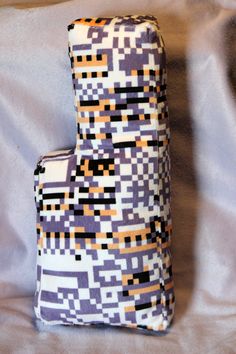 two pieces of fabric sitting on top of a white cloth covered bed sheet with an orange and black pattern