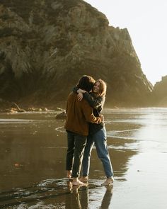 two people hugging each other on the beach