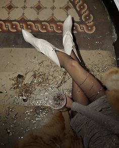 a woman in fishnet stockings and white shoes laying on the floor with her legs crossed