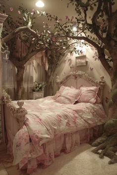 a bedroom decorated in pink and white with flowers on the bed, tree branches over the headboard