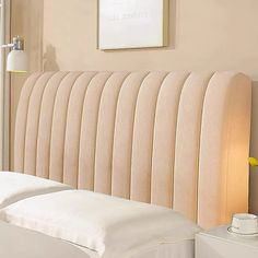 the headboard of a bed with white sheets and pillows on top of it in a bedroom