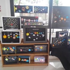 there are many solar system pictures on the shelf in front of the window with black cloth