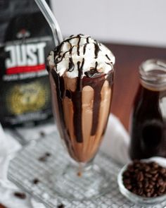 there is a chocolate milkshake with whipped cream on top and coffee beans around it