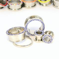 an assortment of metal rings with different colors and sizes on white background, surrounded by smaller ones