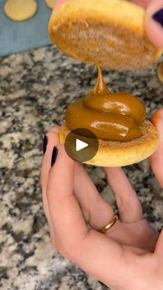 a person holding a donut with peanut butter on it and dipping the doughnut