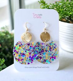 Confetti Lightweight Fun Glitter Earrings, the perfect accessory to add a pop of joy and sparkle to any outfit! Crafted with care from high-quality acrylic, these earrings are both lightweight and durable, ensuring comfort and longevity with every wear. Measuring at a delightful 1.40 inches in diameter and 2-2.25 inches in height, these round earrings boast a playful yet sophisticated design. Each earring is adorned with a mesmerizing array of vibrant confetti-style glitter and gold brass brushe Multicolor Round Earrings For Birthday, Trendy Glitter Gold Earrings, Trendy Gold Glitter Earrings, Fun Gold Jewelry For Party, Fun Small Hoop Earrings As Gift, Fun Small Hoop Jewelry For Gifts, Fun Small Hoop Jewelry Gift, Glitter Round Earrings For Gifts, Playful Gold Earrings For Party