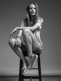 a woman sitting on top of a chair with her legs crossed in front of her