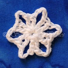 a white crochet snowflake on a blue fabric background with the wording written below it