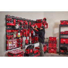 a man is working on the wall in his garage with many tools and equipment behind him