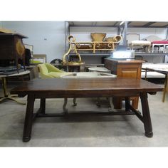 an old wooden table in a shop with chairs and other items on the shelves behind it