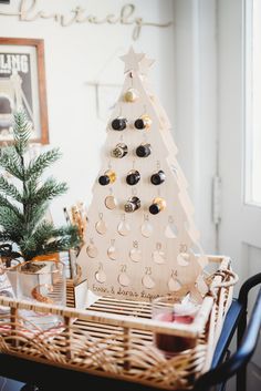 a wooden christmas tree sitting on top of a table next to a basket filled with wine bottles