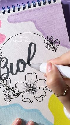 a woman is writing on a notebook with flowers and the word bol written in black ink