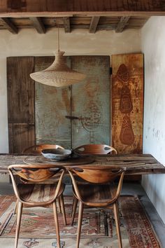 a wooden table with two chairs in front of it and a painting on the wall behind it